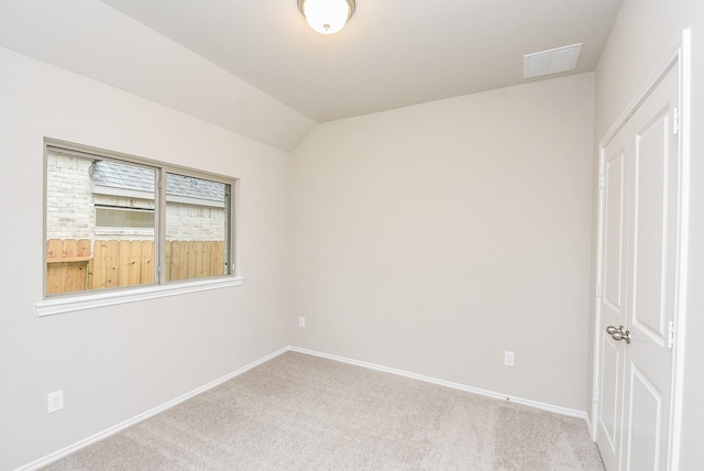 unfurnished bedroom with light colored carpet and vaulted ceiling