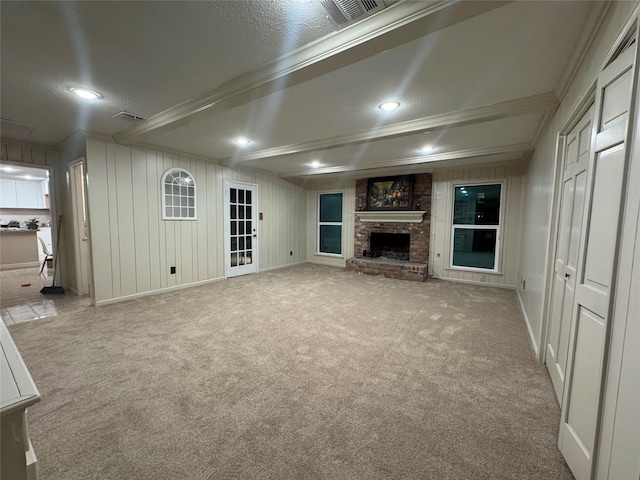 unfurnished living room featuring a fireplace, light colored carpet, a textured ceiling, and ornamental molding