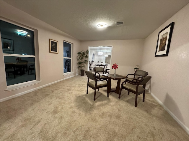 dining room featuring a textured ceiling and light carpet