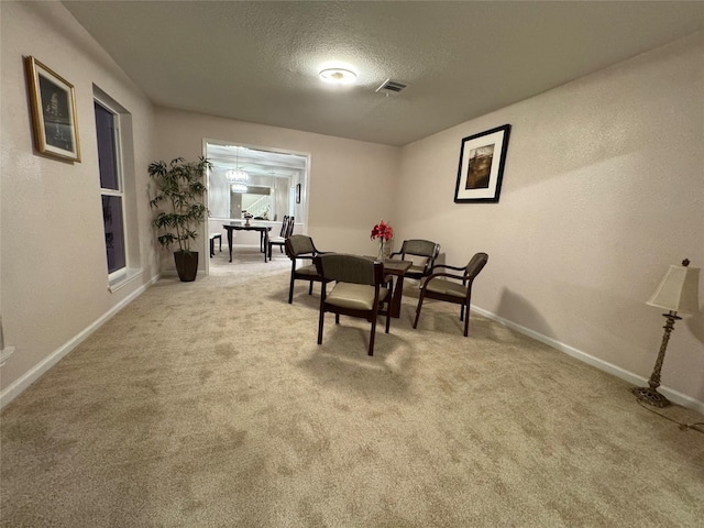 carpeted dining room featuring a textured ceiling