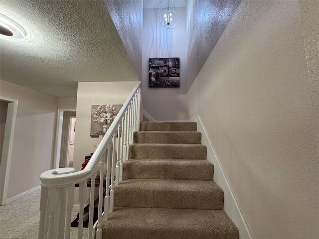 stairway with tile patterned flooring, a textured ceiling, and a chandelier