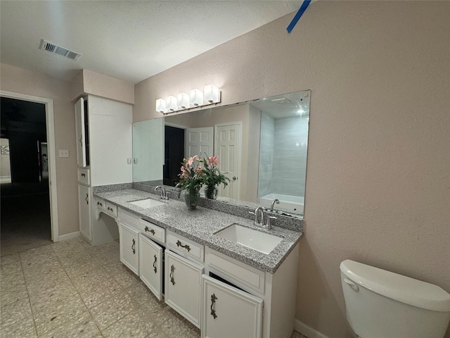 bathroom with vanity, a bath, and toilet