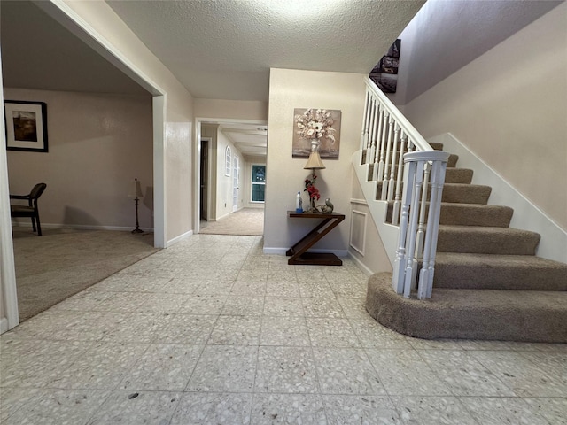 foyer featuring carpet flooring and a textured ceiling