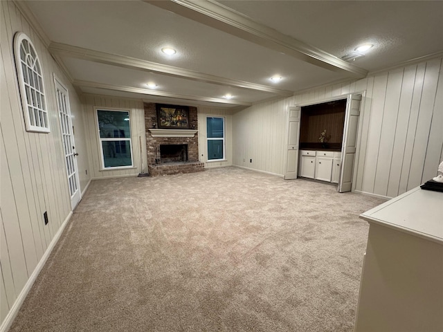 unfurnished living room featuring crown molding, wood walls, a fireplace, and light colored carpet