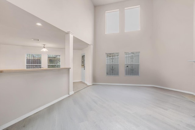 spare room with a towering ceiling and light hardwood / wood-style floors