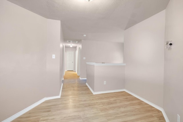 hall with light wood-type flooring and a textured ceiling