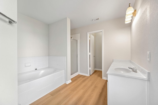 bathroom featuring hardwood / wood-style flooring, vanity, and independent shower and bath