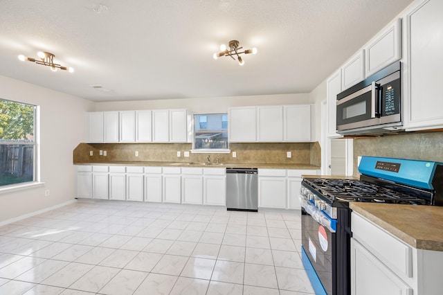 kitchen with white cabinets, light tile patterned flooring, sink, and stainless steel appliances