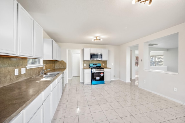 kitchen with sink, light tile patterned floors, tasteful backsplash, white cabinetry, and range with gas cooktop