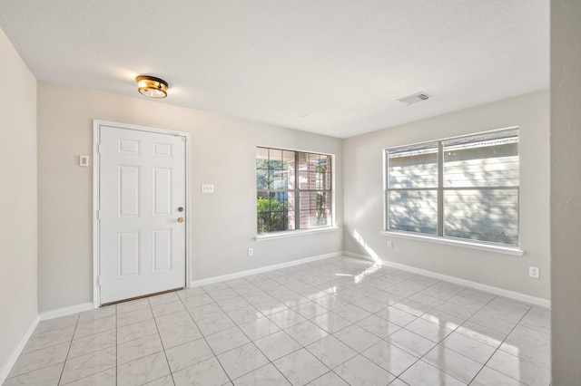 entrance foyer with light tile patterned floors and a textured ceiling