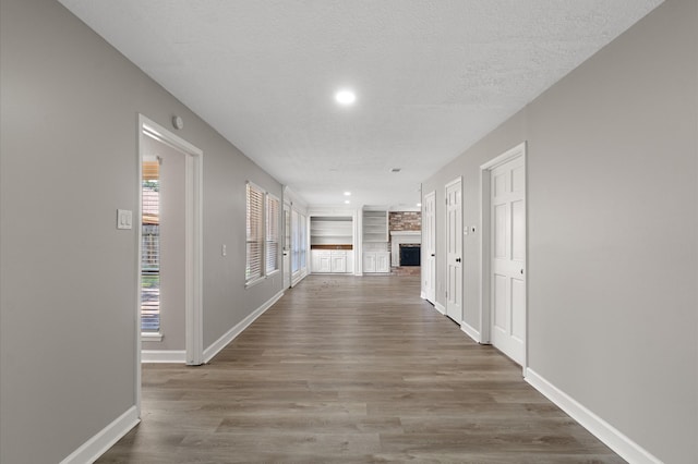 corridor featuring a textured ceiling, built in features, and dark wood-type flooring