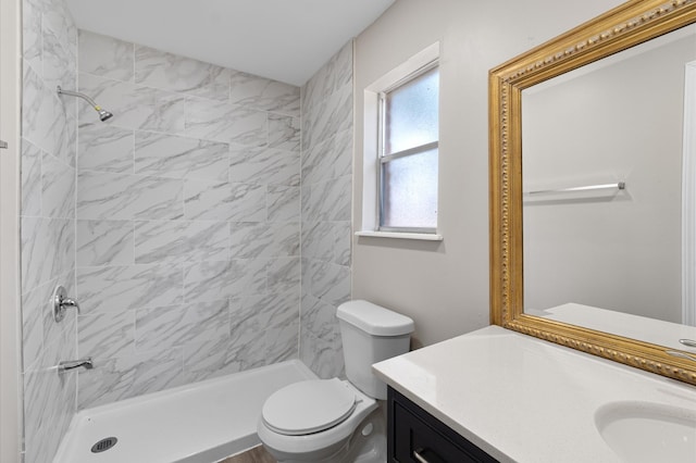 bathroom featuring a tile shower, vanity, and toilet