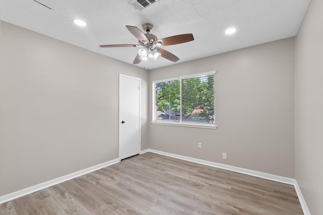 spare room with ceiling fan, light wood-type flooring, and a textured ceiling