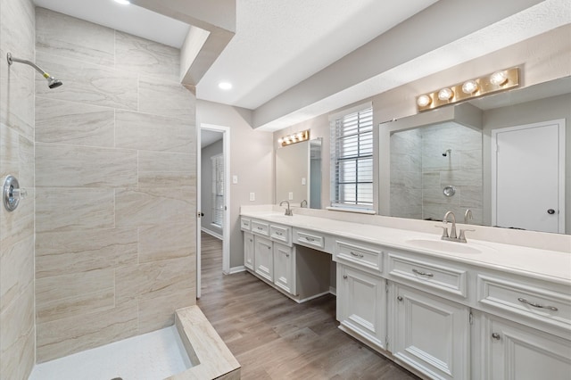 bathroom featuring vanity, a tile shower, and wood-type flooring