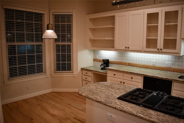 kitchen featuring pendant lighting, black gas stovetop, light hardwood / wood-style flooring, decorative backsplash, and light stone countertops