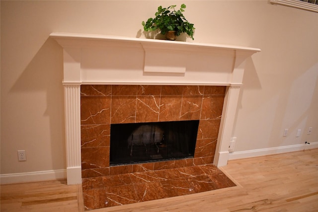 room details featuring wood-type flooring and a tile fireplace