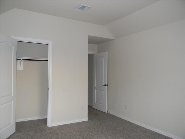 unfurnished bedroom with dark colored carpet, a closet, and vaulted ceiling