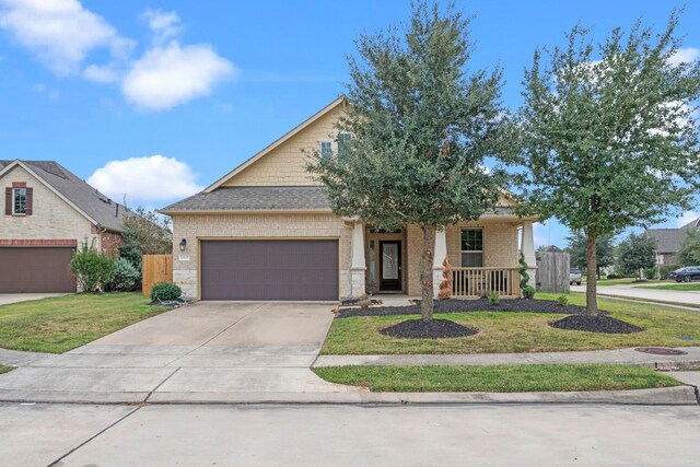 view of front of home with covered porch, a garage, and a front lawn