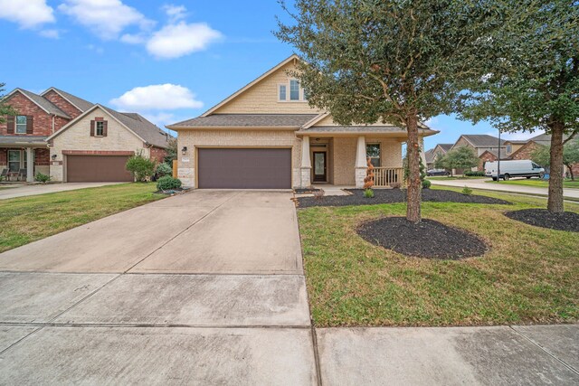 view of front of house featuring covered porch, a garage, and a front lawn