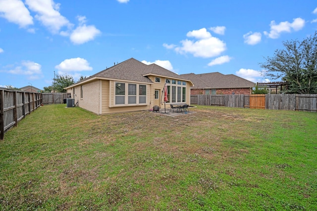 rear view of property with a patio, a yard, and central AC