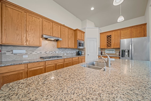 kitchen with sink, stainless steel appliances, light stone counters, tasteful backsplash, and decorative light fixtures