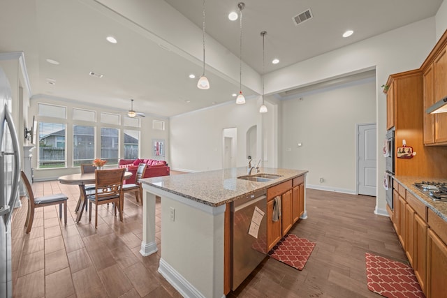 kitchen featuring appliances with stainless steel finishes, an island with sink, sink, dark hardwood / wood-style flooring, and hanging light fixtures