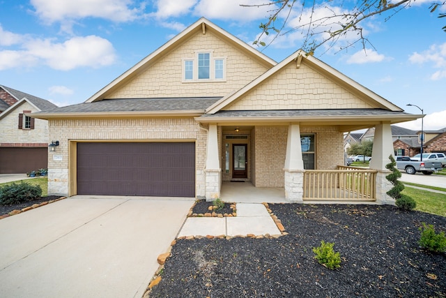 craftsman-style home featuring covered porch, concrete driveway, a shingled roof, a garage, and brick siding