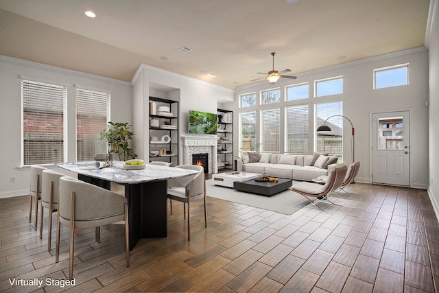 dining room featuring a tile fireplace, crown molding, and wood tiled floor