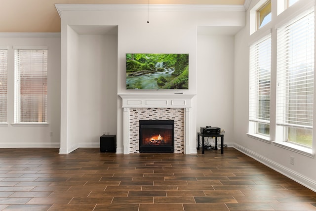 unfurnished living room featuring plenty of natural light, dark wood-type flooring, crown molding, and a tile fireplace