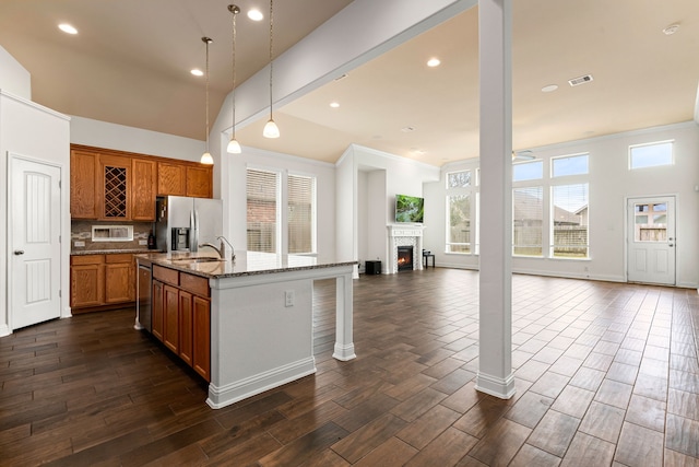 kitchen featuring visible vents, dark stone countertops, open floor plan, dark wood finished floors, and appliances with stainless steel finishes