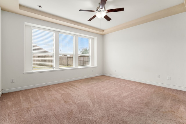 spare room with a tray ceiling, baseboards, and carpet floors