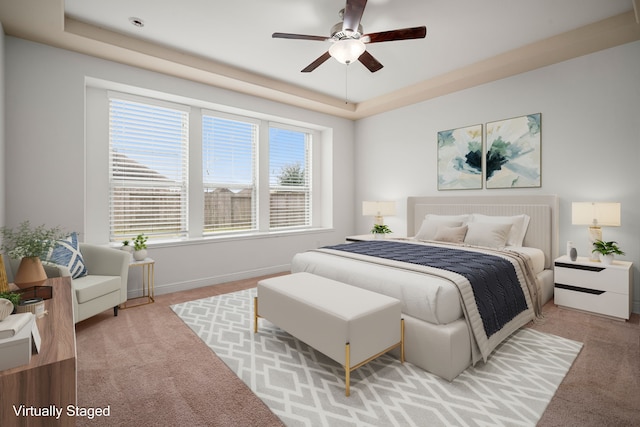 bedroom featuring light colored carpet, a raised ceiling, baseboards, and ceiling fan