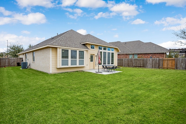 rear view of house featuring brick siding, roof with shingles, a lawn, a fenced backyard, and a patio