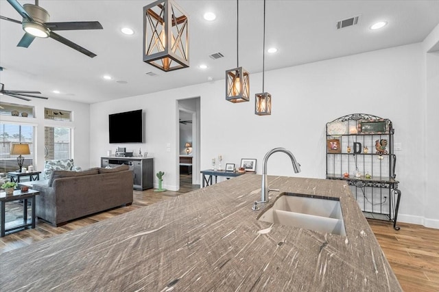 kitchen featuring stone countertops, visible vents, a sink, and wood finished floors