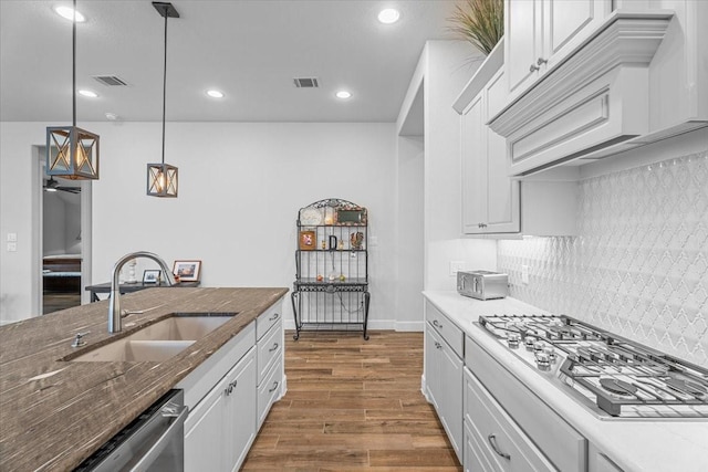 kitchen with decorative light fixtures, visible vents, appliances with stainless steel finishes, white cabinets, and a sink