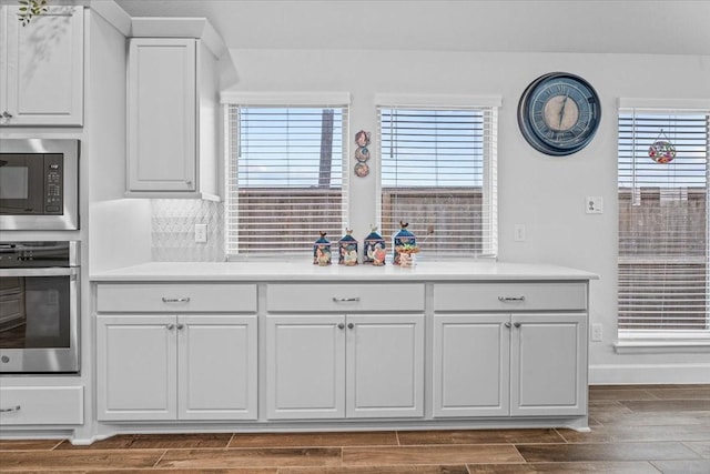 kitchen featuring wood finish floors, white cabinetry, baseboards, light countertops, and appliances with stainless steel finishes