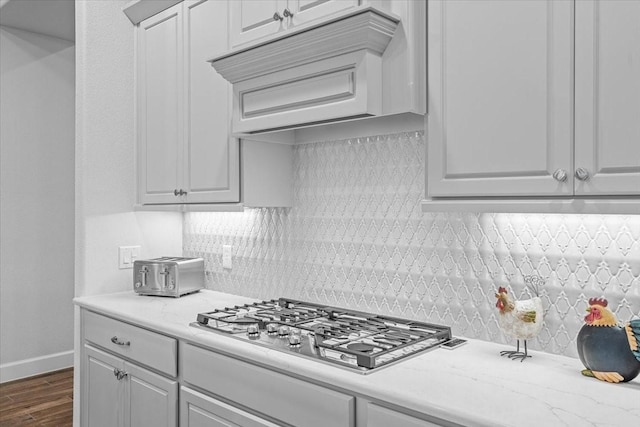 kitchen with dark wood-style floors, premium range hood, stainless steel gas stovetop, and tasteful backsplash