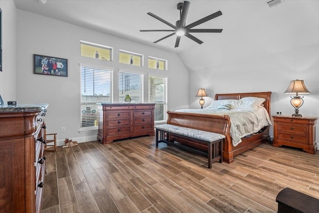 bedroom with lofted ceiling, baseboards, visible vents, and wood finished floors