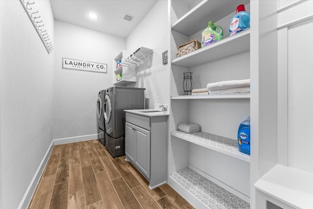 laundry room with cabinet space, dark wood-type flooring, a sink, washer and dryer, and baseboards