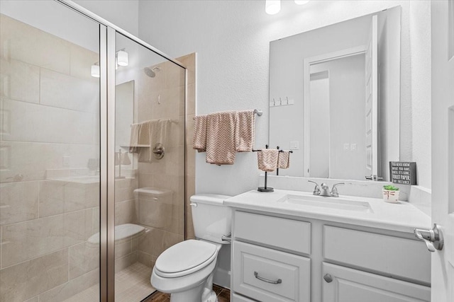 bathroom featuring toilet, a stall shower, and vanity