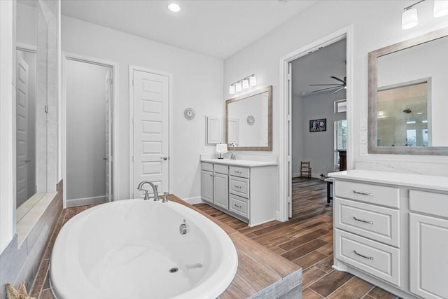 bathroom with wood finish floors, a freestanding bath, vanity, and baseboards