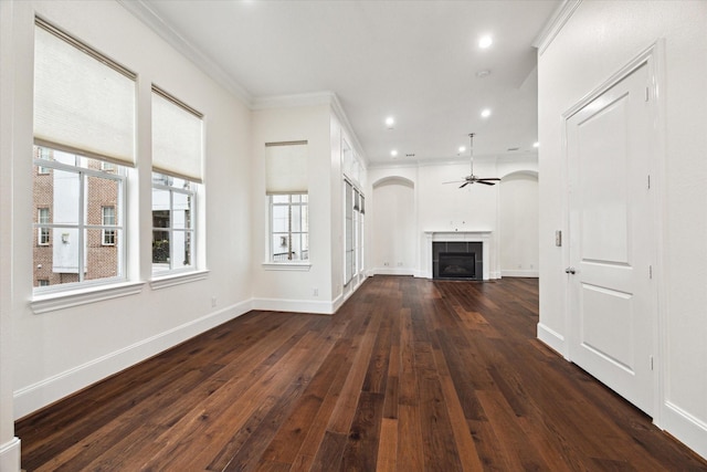 unfurnished living room featuring a tile fireplace, ornamental molding, ceiling fan, and dark wood-type flooring