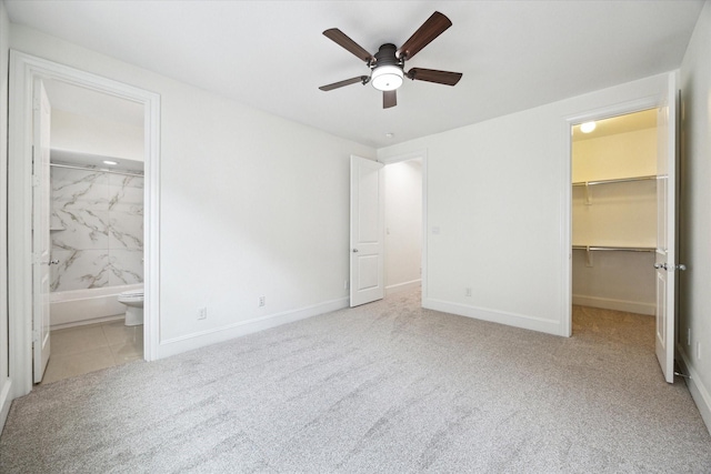 unfurnished bedroom featuring light carpet, ensuite bathroom, ceiling fan, a spacious closet, and a closet