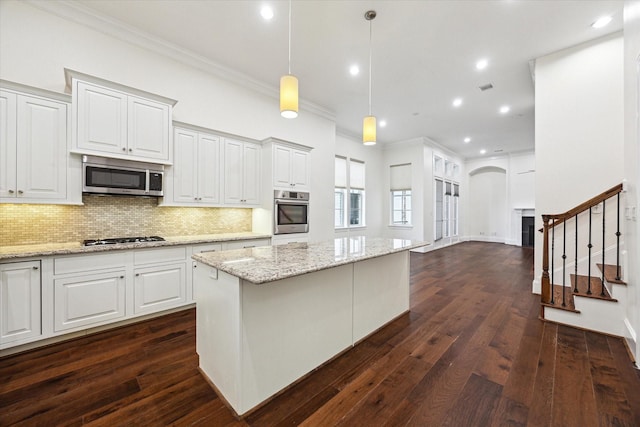 kitchen featuring dark hardwood / wood-style flooring, stainless steel appliances, crown molding, decorative light fixtures, and white cabinetry