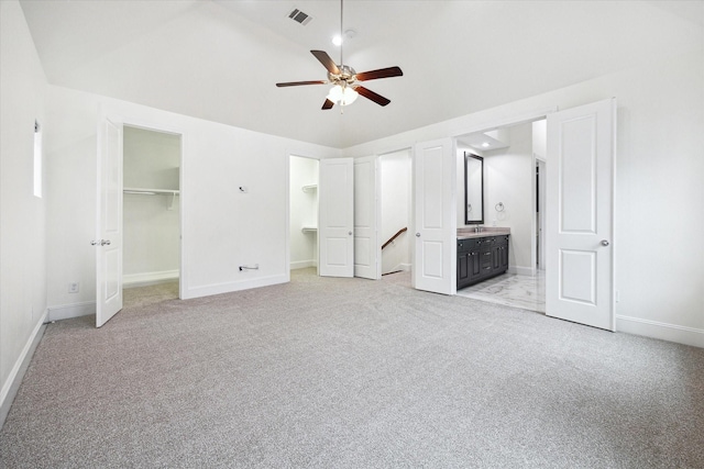 unfurnished bedroom with ceiling fan, light colored carpet, a walk in closet, and connected bathroom