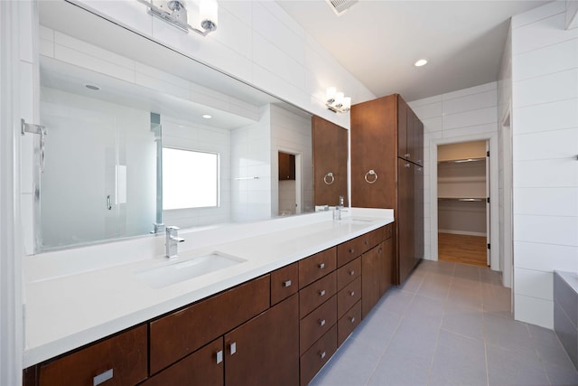 bathroom with tile patterned flooring, vanity, tile walls, and walk in shower