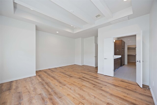 empty room with beamed ceiling and light hardwood / wood-style floors