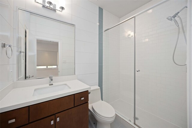 bathroom featuring vanity, a shower with shower door, and toilet