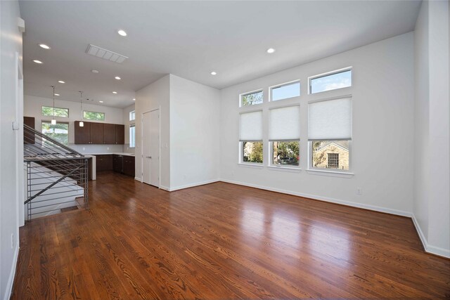 unfurnished living room with a wealth of natural light and dark hardwood / wood-style flooring