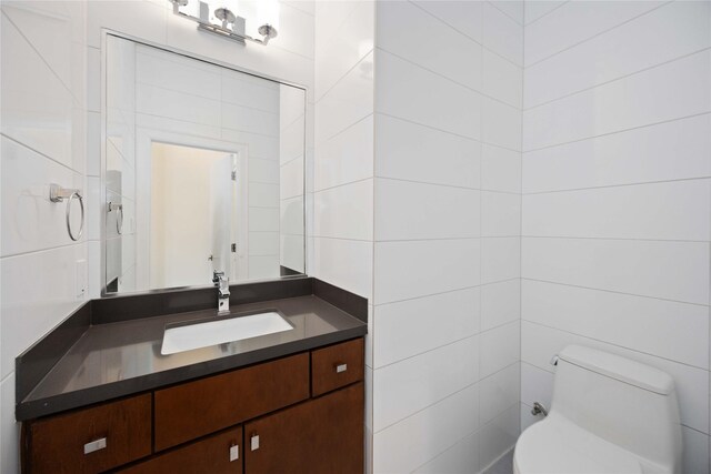 bathroom featuring vanity, tile walls, and toilet